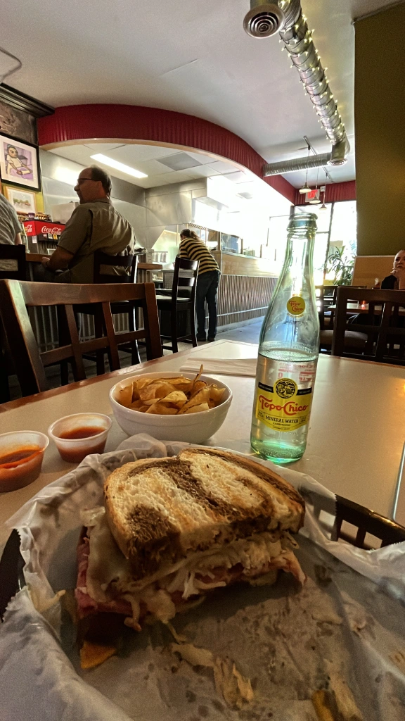 Reuben sandwich with chips and sparkling water.